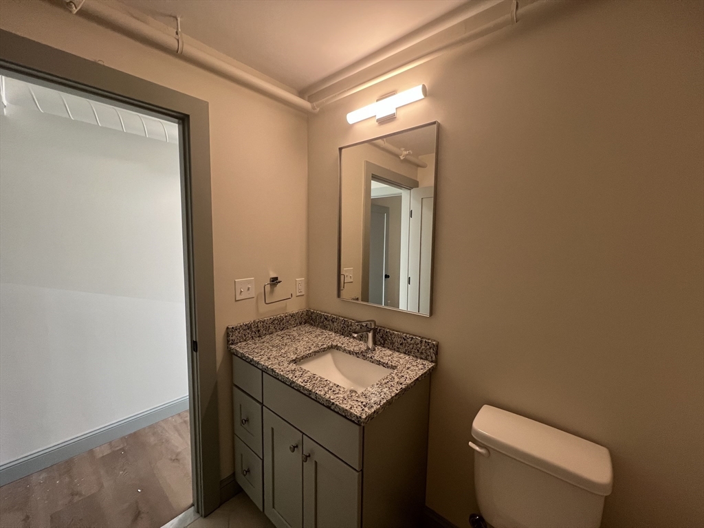 160 Seabury Street, Unit 32 Fall River, MA 02720 - Photo 11 of 14 a bathroom with a granite countertop toilet a sink and a mirror