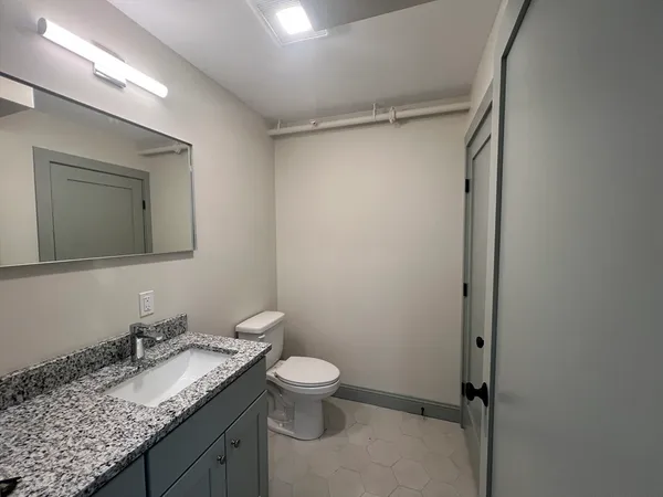 a bathroom with a granite countertop sink toilet and mirror