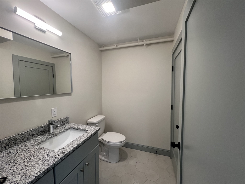 160 Seabury Street, Unit 32 Fall River, MA 02720 - Photo 4 of 14 a bathroom with a granite countertop sink toilet and mirror