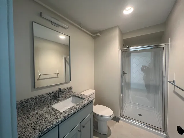 a bathroom with a granite countertop sink toilet and shower