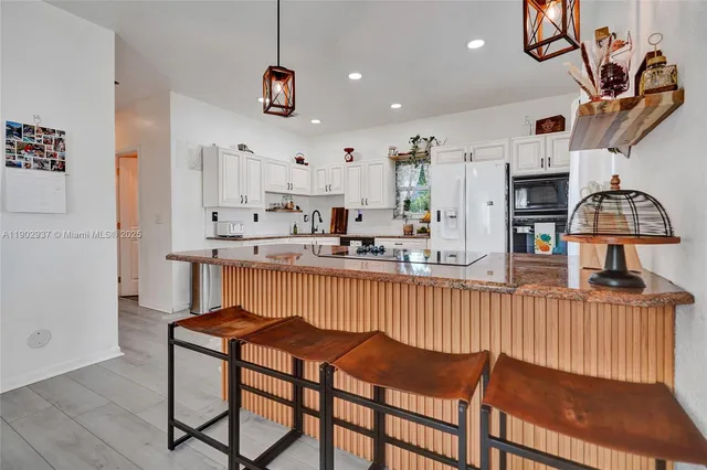 a kitchen with stainless steel appliances kitchen island granite countertop a table chairs in it and wooden floors