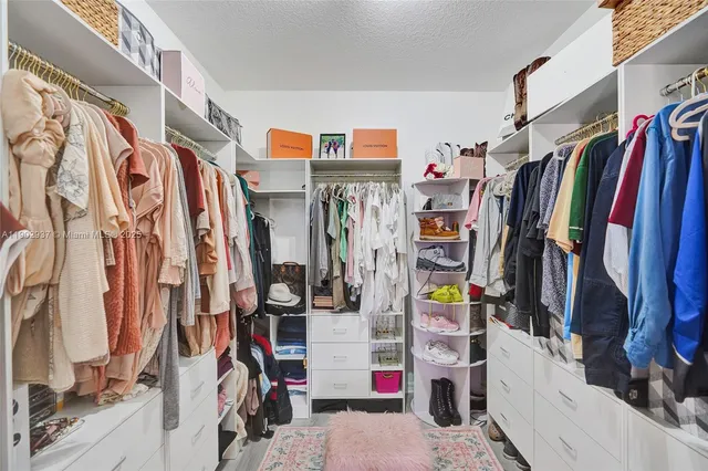 a view of walk in closet with clothes and shoes