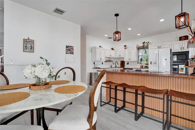 a dining table with kitchen island stainless steel appliances and wooden floor