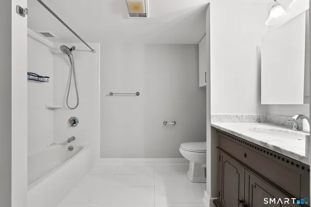 a bathroom with a granite countertop sink a toilet and shower