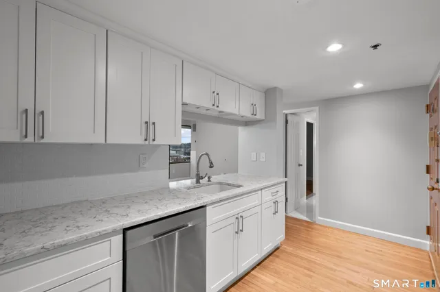 a kitchen with granite countertop cabinets stainless steel appliances a sink and wooden floor