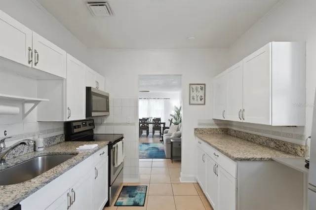 a kitchen with granite countertop a sink and white cabinets