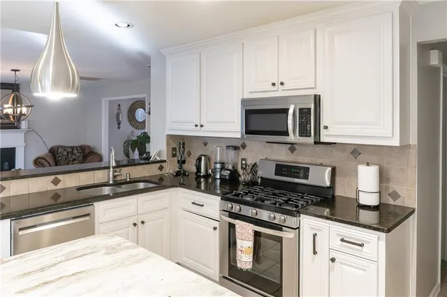 a kitchen with granite countertop white cabinets and stainless steel appliances