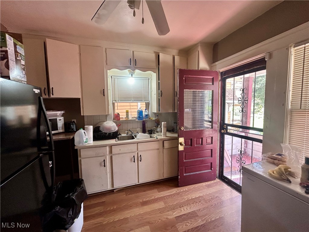 10202 Kinsman Road Cleveland, OH 44104 - Photo 6 of 15 Kitchen featuring freestanding refrigerator, light countertops, light wood-style flooring, backsplash, and white cabinetry