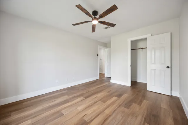 an empty room with wooden floor and ceiling fan