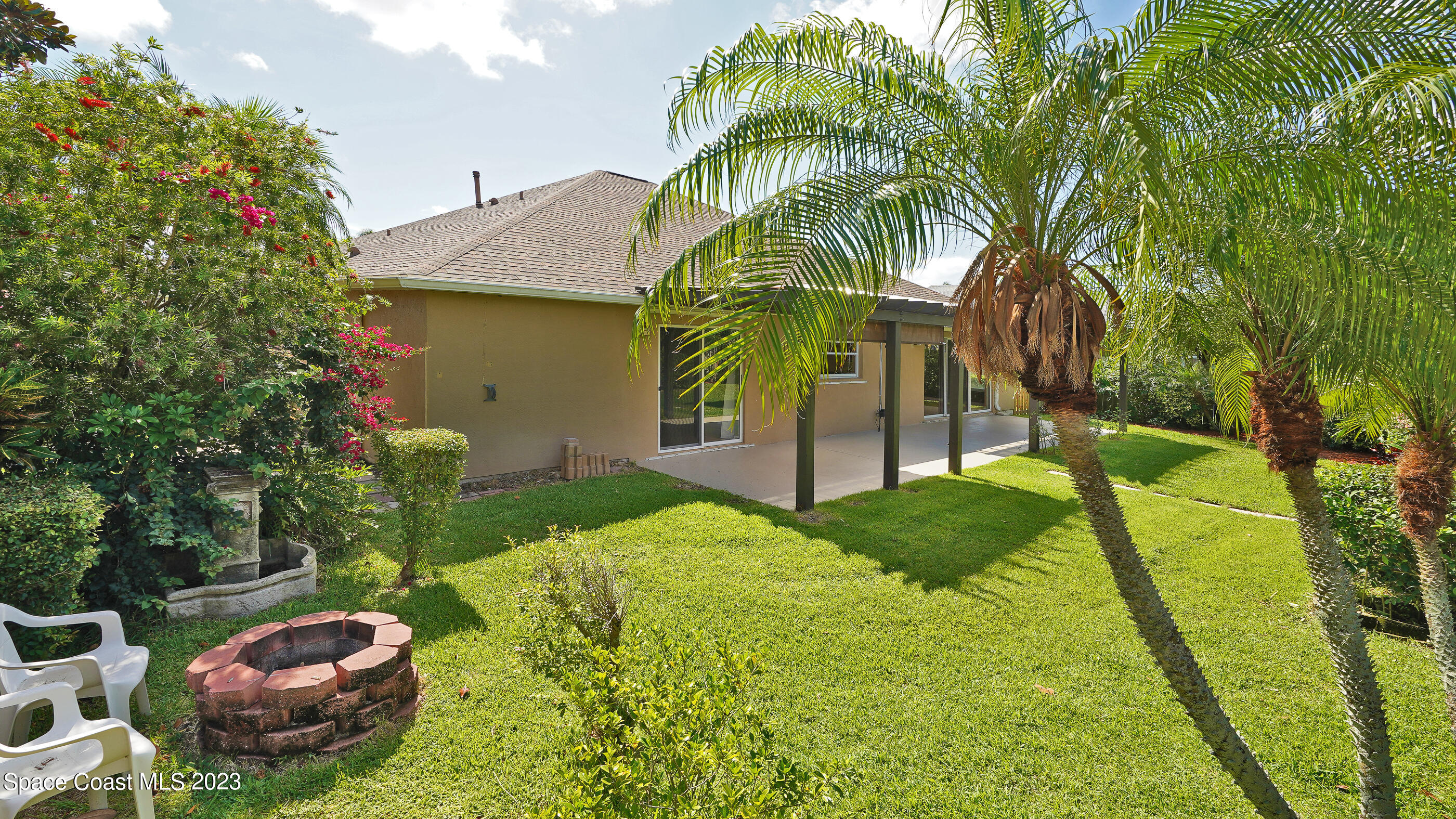 395 Brookcrest Circle Rockledge, FL 32955 - Photo 14 of 44 a backyard of a house with table and chairs plants and large tree