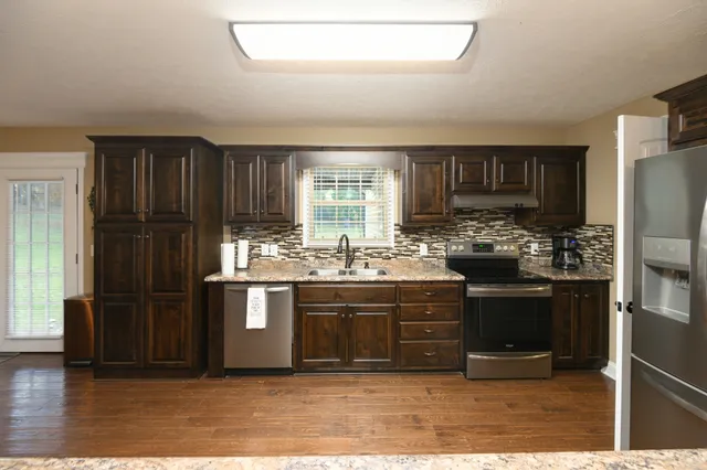 a view of a dining room and livingroom with furniture wooden floor a chandelier