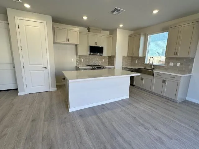 a large kitchen with stainless steel appliances granite countertop a stove a sink and a refrigerator