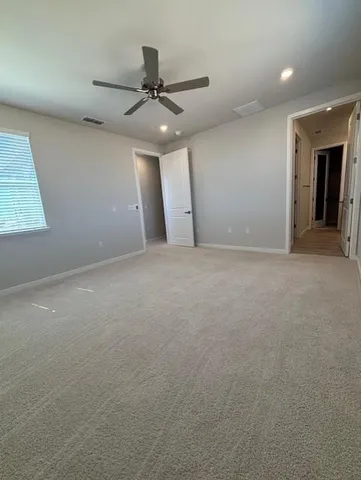 an empty room with a ceiling fan and window