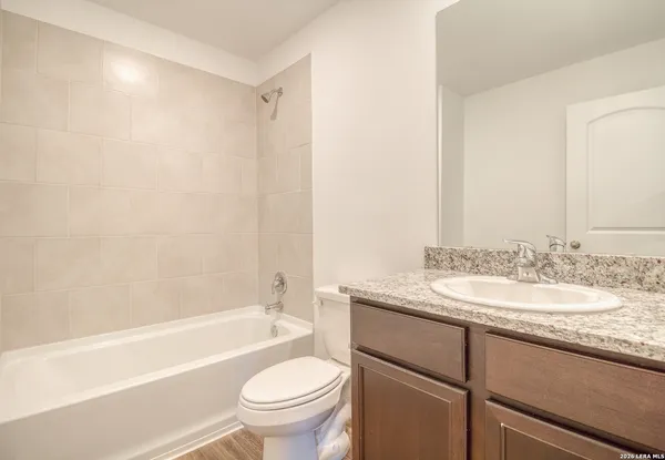 a bathroom with a granite countertop sink toilet mirror and bathtub