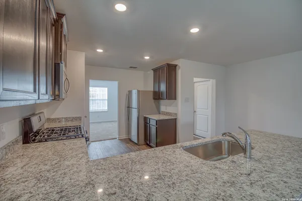 a kitchen with stainless steel appliances granite countertop a sink a stove and a refrigerator