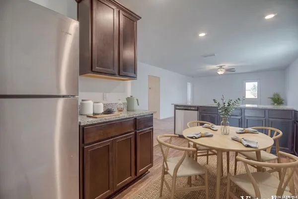 a kitchen with stainless steel appliances granite countertop a sink a stove a refrigerator with a dining table and chairs