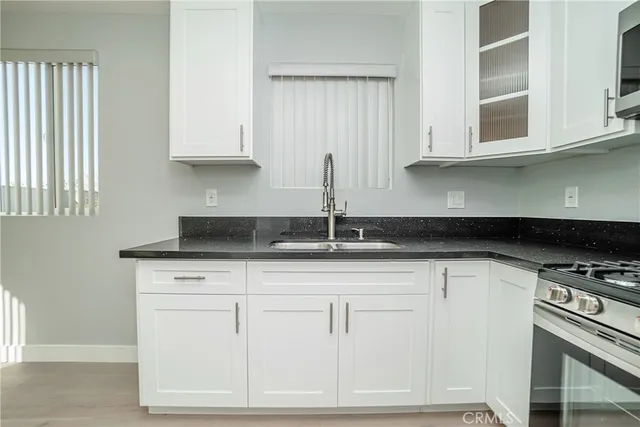a kitchen with stainless steel appliances granite countertop a sink a stove and cabinets