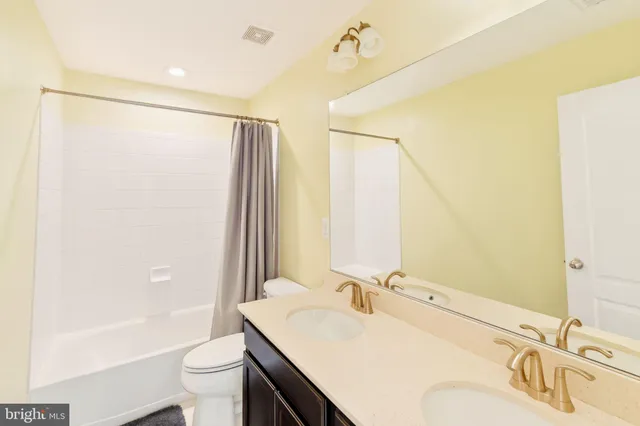a bathroom with a toilet sink vanity and mirror