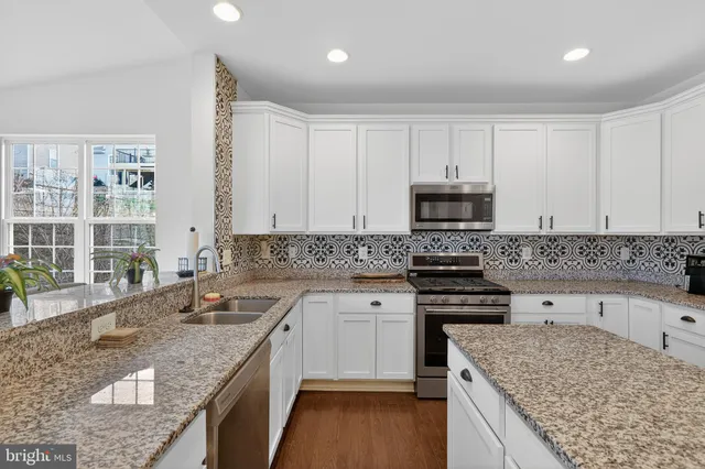a kitchen with granite countertop a sink stove and cabinets