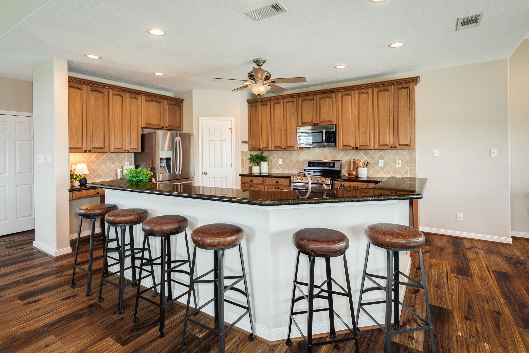 11648 Zingelmann Road Galveston, TX 77554 - Photo 12 of 39 a kitchen with stainless steel appliances granite countertop a table chairs refrigerator and cabinets