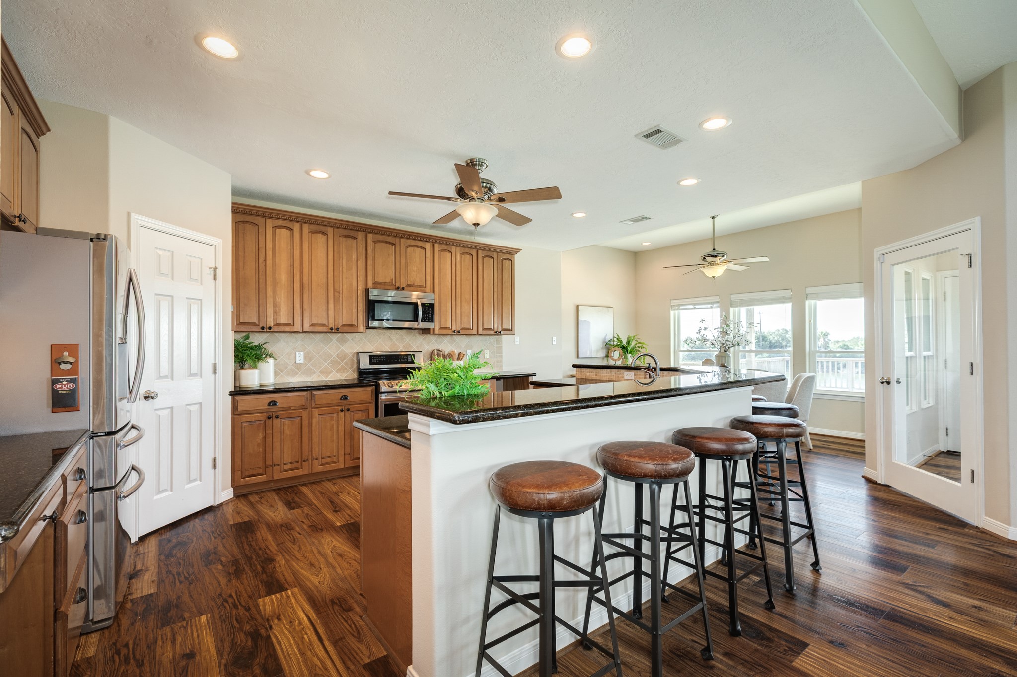 11648 Zingelmann Road Galveston, TX 77554 - Photo 13 of 39 a kitchen with stainless steel appliances a dining table chairs stove and refrigerator