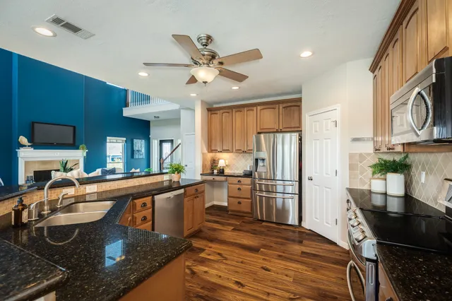 a kitchen with stainless steel appliances granite countertop a sink refrigerator stove and microwave