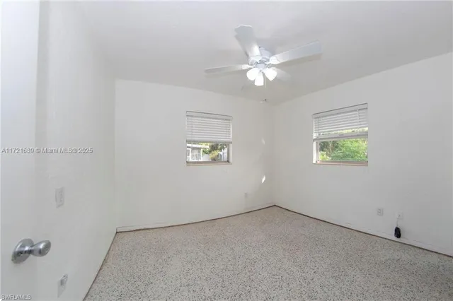 an empty room with a window and a fan
