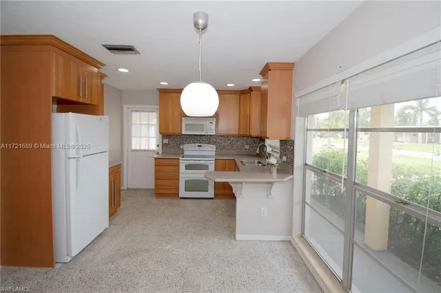 a open kitchen with white cabinets and a refrigerator