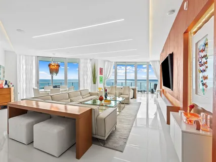 a living room with stainless steel appliances kitchen island furniture a flat screen tv and a large window