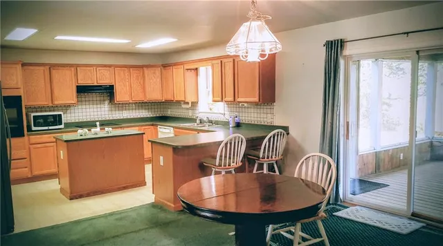 a kitchen with stainless steel appliances granite countertop a dining table chairs and a refrigerator