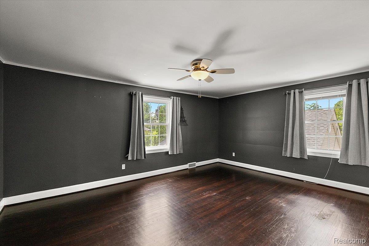 1051 Devonshire Road Grosse Pointe, MI 48230 - Photo 33 of 99 Spacious room featuring dark wood-finish flooring, two large windows, white trim, and a ceiling fan with integrated lighting