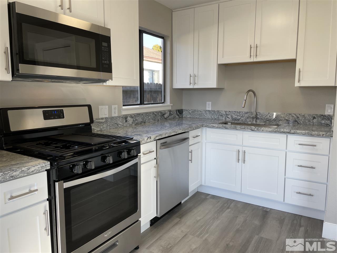 1440 Upton Way Sparks, NV 89431 - Photo 9 of 28 a kitchen with granite countertop white cabinets stainless steel appliances and sink