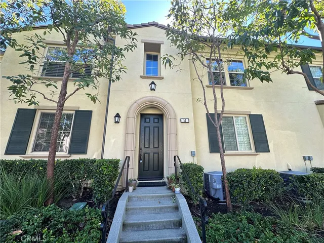 a front view of a house with brick walls and plants