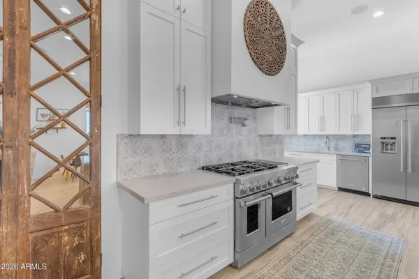 a kitchen with granite countertop a sink stainless steel appliances and white cabinets