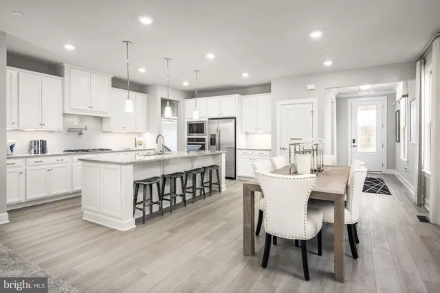 a large kitchen with kitchen island a dining table chairs and white cabinets