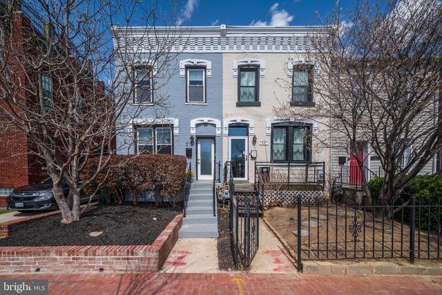 a front view of a house with large trees