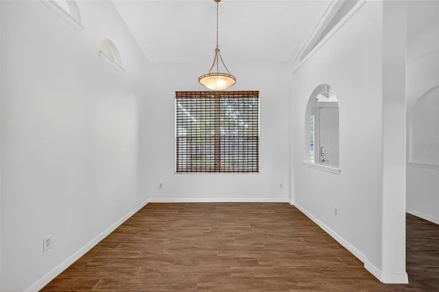 a view of an empty room with wooden floor and windows