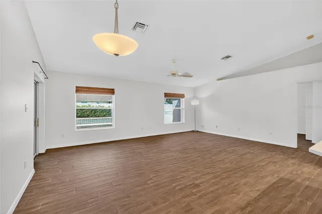 a view of an empty room with a window and wooden floor