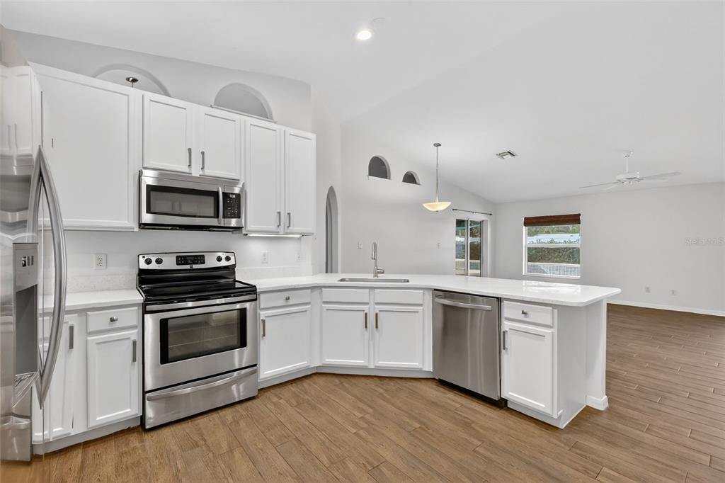 2113 Wolf Ridge Lane Mount Dora, FL 32757 - Photo 22 of 49 a kitchen with stainless steel appliances granite countertop a stove top oven a sink and white cabinets