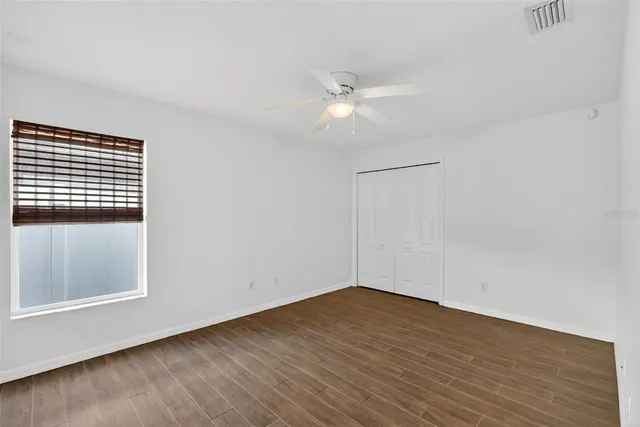 a view of an empty room with wooden floor and a window