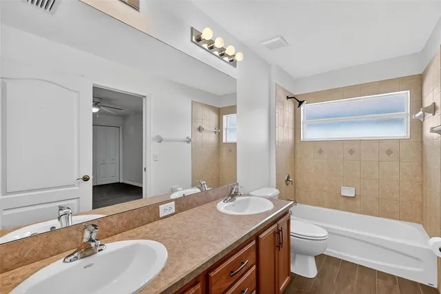 a bathroom with a granite countertop double vanity sink toilet mirror and bathtub