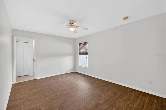 a view of empty room with wooden floor and fan