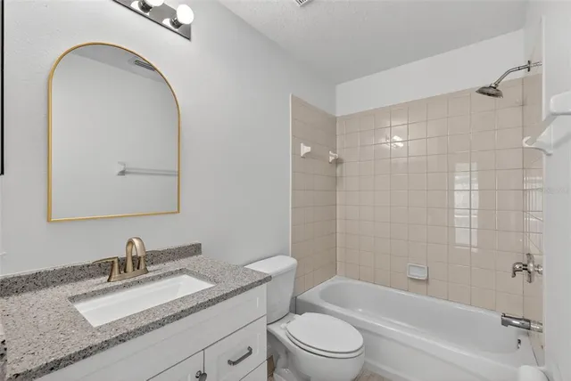 a bathroom with a granite countertop sink a mirror a toilet and shower