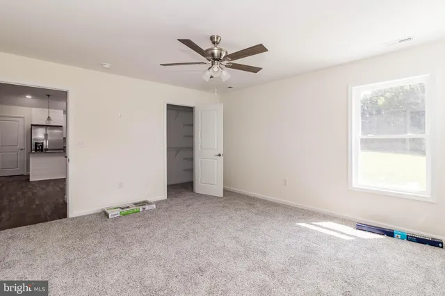 a view of a livingroom with a ceiling fan & cabinets