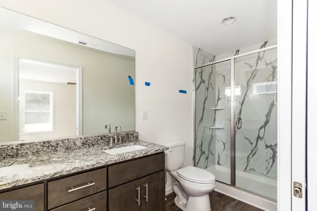 a bathroom with a granite countertop sink toilet and shower
