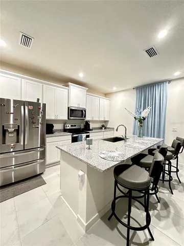 a kitchen with stainless steel appliances kitchen island granite countertop a table chairs microwave and sink