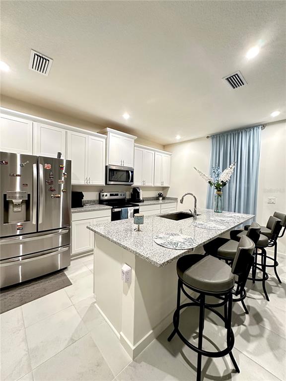 a kitchen with stainless steel appliances kitchen island granite countertop a table chairs microwave and sink