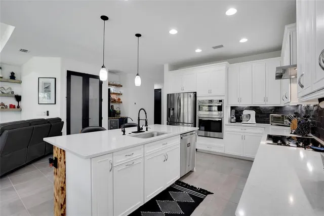 a large kitchen with kitchen island a large counter space a sink appliances and a living room view