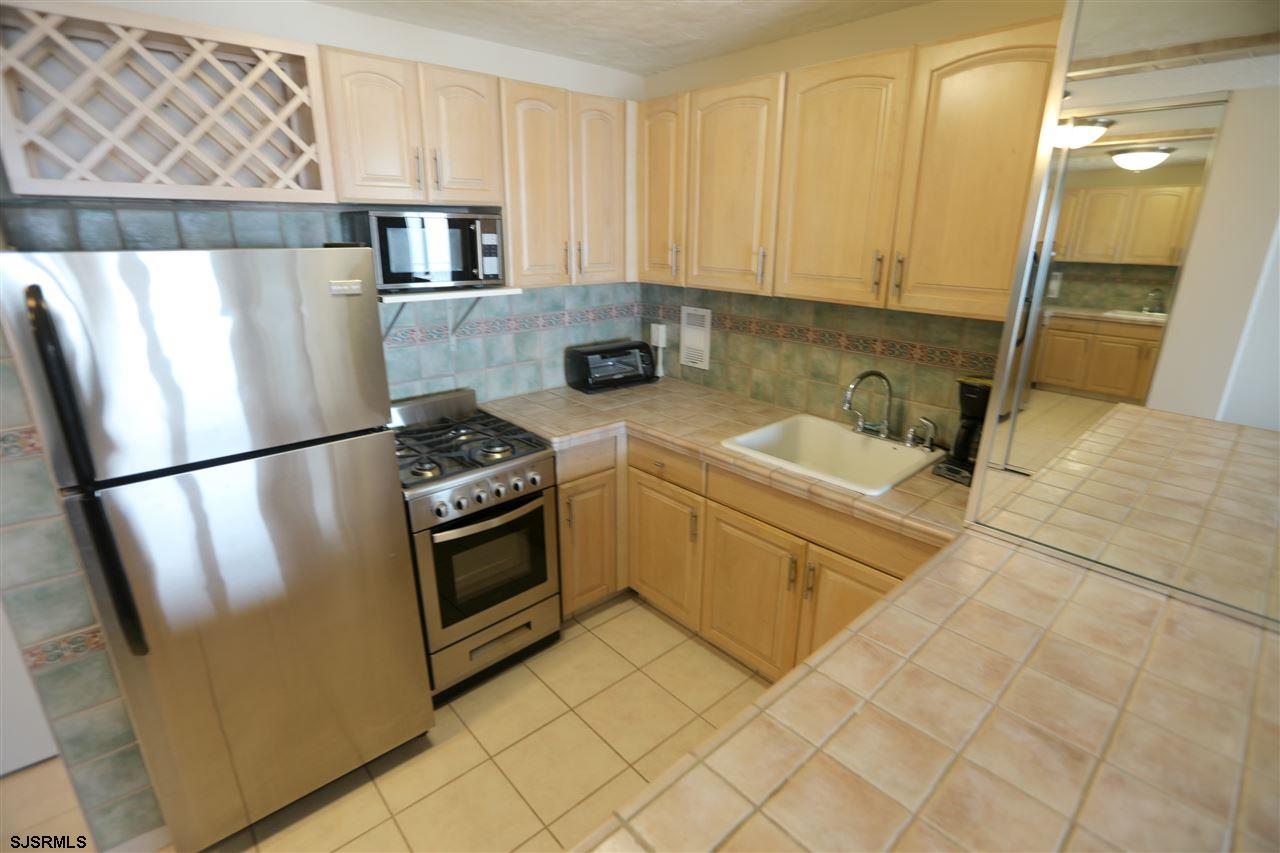 9400 Atlantic Avenue, Unit 709 Margate City, NJ 08402 - Photo 2 of 11 a kitchen with a refrigerator sink and cabinets