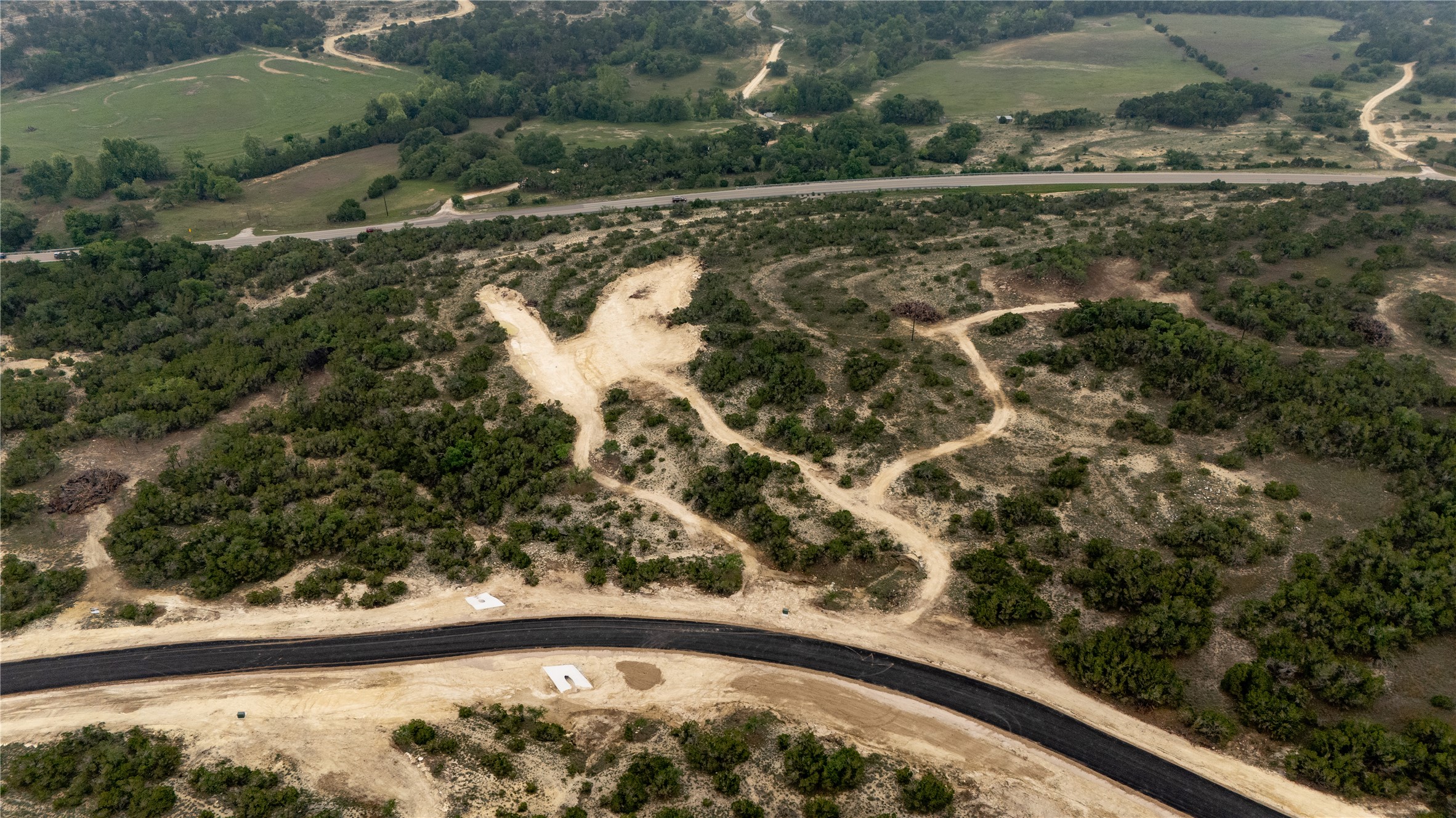 Lot 3 Ranch Road 165 Dripping Springs, TX 78620 - Photo 4 of 11 Aerial perspective showcasing a newly paved road winding through varied terrain